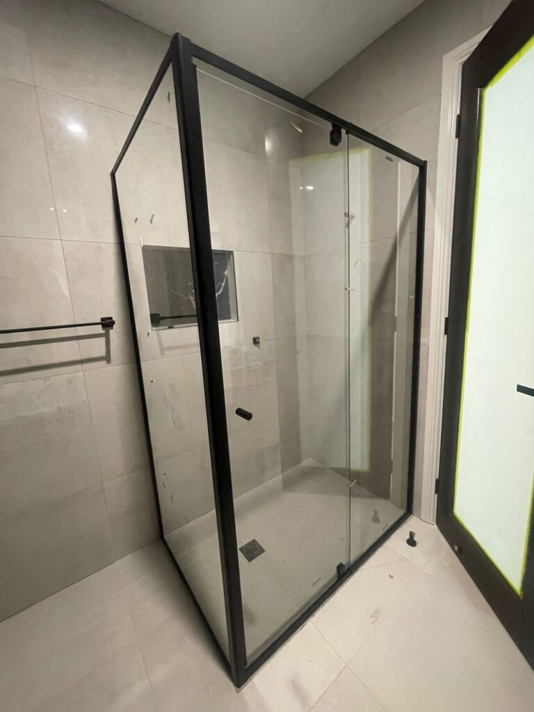 Corner glass shower enclosure with matte black metal frame